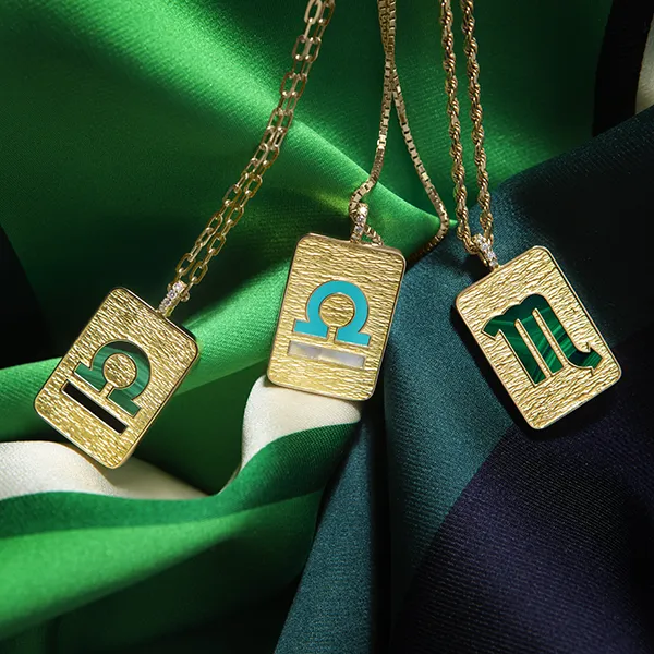 Pendentifs en or gravés mis en scène sur un tissu vert